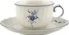 A white teacup and saucer with blue floral accents and trim, set against a white background. Produktbild-Vorschau