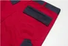 A close-up view of the back pocket and side of red work pants with dark gray accents. Produktbild-Vorschau