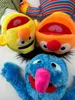 A close-up overhead shot of three Sesame Street puppets: Ernie (yellow), Bert (orange), and Grover (blue). Produktbild-Vorschau