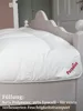 A close-up of a white duvet on a bed with a decorative headboard. Produktbild-Vorschau