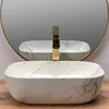 A marble-patterned vessel sink with a gold faucet is shown in front of a round mirror. Náhľad obrázku produktu