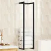 A black metal towel rack holding several rolled white towels, mounted on a wall with cream-colored rectangular tiles. Anteprima dell’immagine prodotto
