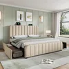 A bedroom scene featuring a beige upholstered bed with storage drawers, bedside tables, and wall art. Náhľad obrázku produktu