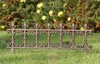 A decorative metal garden border fence is placed on a grassy lawn in front of a flowering bush. Produktbild-Vorschau