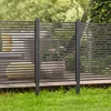 A modern fence with horizontal slats is shown in a garden setting, with grass in the foreground and trees in the background. Náhled obrázku produktu