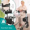 A woman is sitting on a rollator, which is a mobility aid. The image highlights features of the rollator. Produktbild-Vorschau
