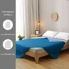 A bedroom scene showing a blue quilted blanket on a bed. Produktbild-Vorschau