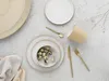 A flat lay of a stoneware dinnerware set with quail eggs, cutlery, and a cup. Produktbild-Vorschau
