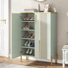 A shoe cabinet with its door open, displaying shoes on shelves, placed in a room with a door and textured wallpaper. Produktbild-Vorschau