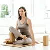 A woman is doing yoga on a mat with yoga blocks. Produktbild-Vorschau
