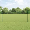 A green fence with two posts in a grassy field with trees in the background. Náhled obrázku produktu