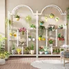 A multi-tiered plant stand filled with various potted plants, displayed indoors on a wooden floor. Anteprima dell’immagine prodotto