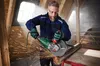 A man is using an angle grinder to cut a metal pipe in a workshop. Produktbild-Vorschau