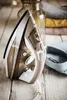 An iron is placed on a wooden surface next to a folded shirt and some glass bottles. Produktbild-Vorschau