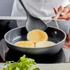 A person is toasting bread in a frying pan on a stove. Produktbild-Vorschau