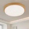 A round LED ceiling light with a wooden frame and a textured, crystal-like diffuser is mounted on a white ceiling. Produktbild-Vorschau