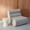 A modern chair and side table in a room with wood-paneled walls. Produktbild-Vorschau