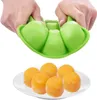 Hands holding a green silicone mold for freezing food, with a plate of orange frozen cubes below. Produktbild-Vorschau