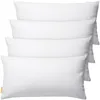 Four white pillows are stacked on top of each other against a white background.