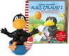 A toy figure of a crow sitting in a blue bowl next to a children's book. Produktbild-Vorschau