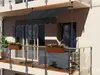 A balcony with a black awning, flower boxes, and glass railings. Náhľad obrázku produktu