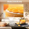 A projector displaying an image of a cake on a screen, with a laptop, tablet, and smartphone also showing the same image, set in a living room environment. Produktbild-Vorschau