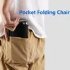 A person is putting a folded compact chair into their back pocket. Produktbild-Vorschau