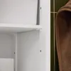 Close-up of a white cabinet shelf and a brown towel hanging next to it on a green tiled wall. Produktbild-Vorschau