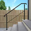 A black metal handrail installed on outdoor stairs next to a wooden fence. Produktbild-Vorschau