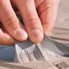 A close-up of a hand peeling off a gray repair tape from a surface. Produktbild-Vorschau