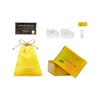 A collection of items, including a yellow drawstring bag, a certificate, a pair of colorful shoes, and a small golden box, arranged on a white background. Voir les images du produit