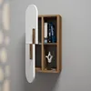 A modern wall shelf with a unique design, featuring a white curved door and a wooden interior with compartments. Produktbild-Vorschau