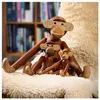 Three wooden monkey figurines are sitting on a fluffy white rug in front of a bookshelf. Náhled obrázku produktu