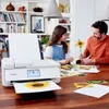 A father and daughter are at a table with a printer and art supplies, printing a sunflower image. Podgląd zdjęcia produktu