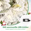 A close-up of a snow-covered artificial Christmas tree with warm white LED lights, accompanied by a small graphic of Santa Claus and a Christmas tree, and a close-up of a power adapter. Produktbild-Vorschau
