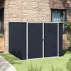 A dark gray metal storage shed is placed on a grassy lawn next to a brick building.