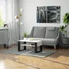 A modern living room with a grey sofa, a white and black coffee table, a floor lamp, and artwork on the wall. Produktbild-Vorschau