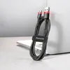 A black and red braided micro USB data/charging cable is coiled and held by a velcro strap with the Baseus logo on it, resting on a laptop. Náhled obrázku produktu