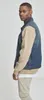 A man wearing a denim vest over a tan sweatshirt and khaki pants, posing against a white background. Produktbild-Vorschau