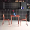 A small outdoor table and two chairs set against a black tiled wall. Produktbild-Vorschau
