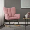 A pink rocking chair in a living room setting, next to a small side table with a vase and mug. Náhled obrázku produktu