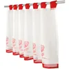 A close-up view of a white bistro curtain with red rose patterns and red trim, hanging from a metal rod. Produktbild-Vorschau