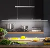 A modern kitchen scene with a pendant light illuminating a countertop with fresh ingredients and cooking pots on the stove. Voir les images du produit