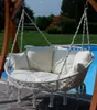 A double hanging lounge chair with cushions is placed next to a swimming pool in a garden setting. Produktbild-Vorschau