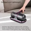 A hand is holding a handheld vacuum cleaner over a light-colored surface, possibly a mattress or sofa. Produktbild-Vorschau