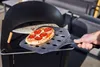 A hand is using a pizza peel to remove a small pepperoni pizza from a black gas pizza oven. Produktbild-Vorschau