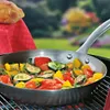 A frying pan filled with colorful vegetables is placed on a grill, with a loaf of bread and a red tablecloth in the background. Voir les images du produit