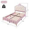 A pink upholstered bed frame with a crown-shaped headboard, shown with dimensions and weight capacity. Podgląd zdjęcia produktu