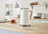 A modern kitchen counter with a white kettle, a cup of tea, and a microwave in the background. Podgląd zdjęcia produktu