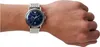 A close-up shot of a man's wrist wearing a silver Emporio Armani watch with a blue dial. Náhled obrázku produktu